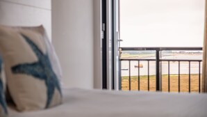 Una habitación de hotel con una cama, una ventana con vista a un cuerpo de agua y un paisaje distante.
