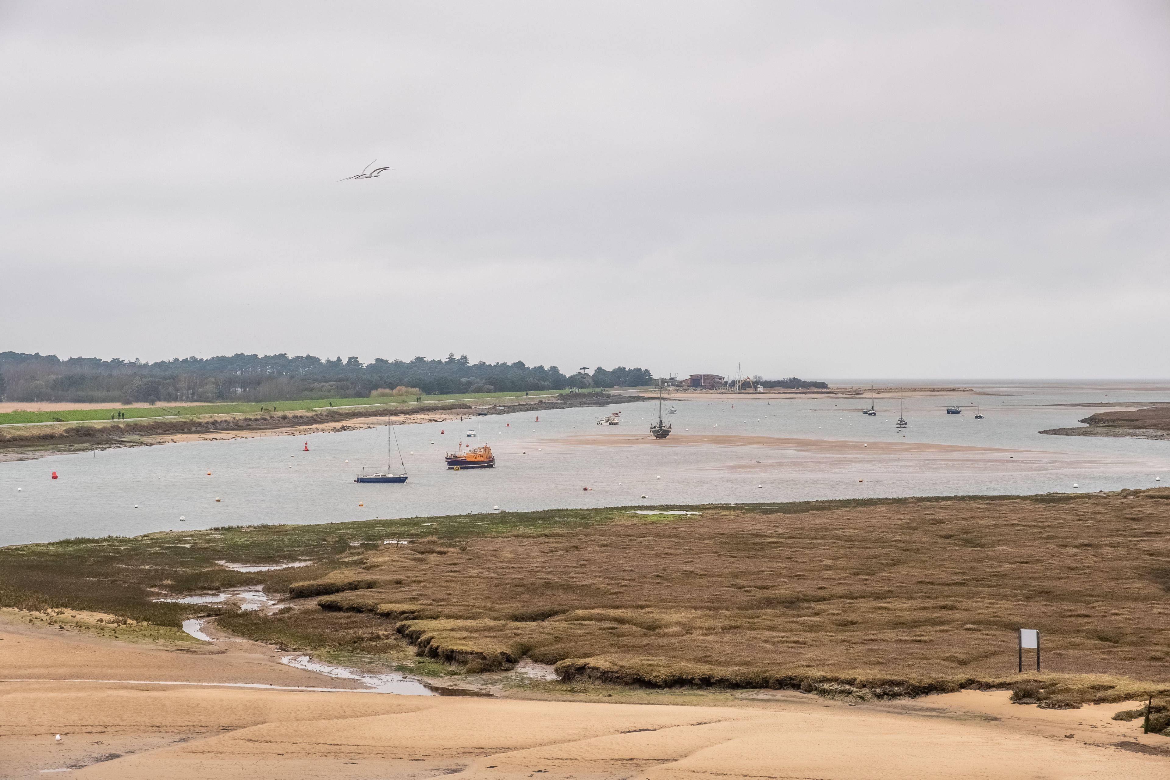 A coastal landscape with a sandy beach, a river, and boats.