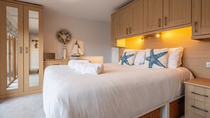 Un dormitorio con una cama grande, armarios de madera, un espejo y una mesita de noche con una lámpara.