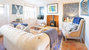 Una sala de estar con sofá, sillón, televisor, chimenea y decoración en la pared.