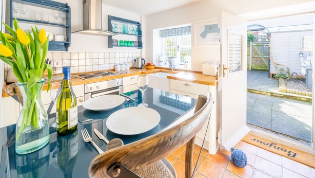 Una cocina moderna con una mesa de vidrio, armarios blancos y un salpicadero azul.