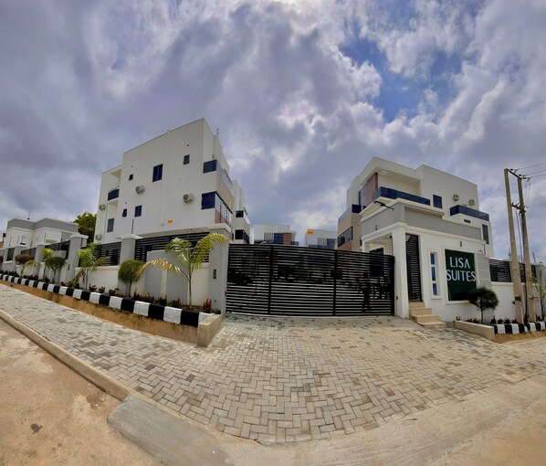 A gated residential complex with modern architecture, featuring a prominent entrance gate and a sign for 'Lisa Suites'. - Lisa Suites (Abuja)