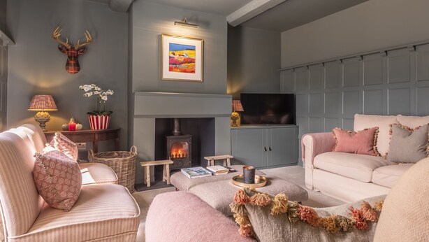 A cozy living room with a fireplace, a mounted deer head, and a framed landscape painting. - Old Mill House, Brancaster, Norfolk (Brancaster)