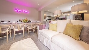 A modern dining area with a neon sign, a white sofa, and a dining table set for six. - Old Mill House, Brancaster, Norfolk (Brancaster)