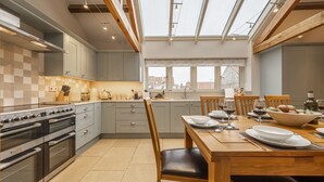 A modern kitchen with a skylight, built-in oven, and dining area with a table set for two. - 6 Courtyard Barn, Docking, Norfolk (Docking)