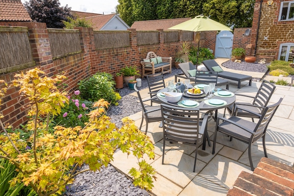 Relax and socialize in this inviting outdoor space, complete with a dining table, lounge chairs, and a sofa.