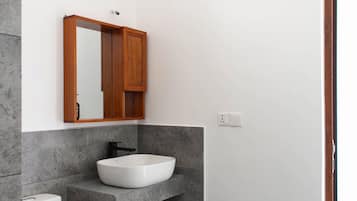 A modern bathroom with a white toilet, a white sink, and a wooden medicine cabinet above the sink.