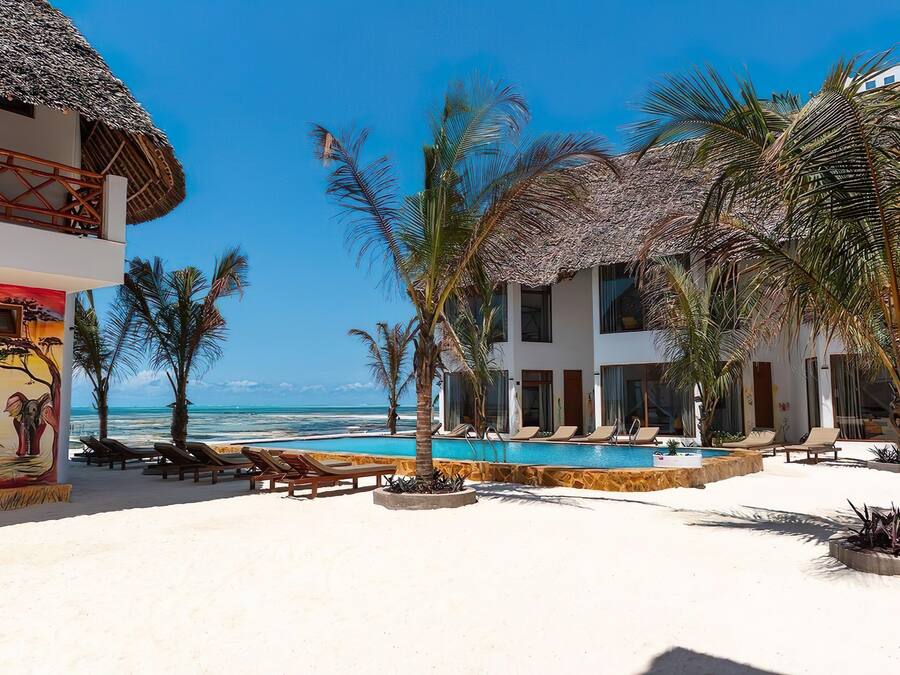 A resort with a pool, lounge chairs, and a view of the ocean.