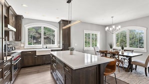 A spacious kitchen with a large island, dark wood cabinets, and a dining area with a table and chairs. - Perfect location! Come and see (Park City)