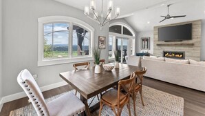 A dining area with a wooden table, chairs, and a chandelier. There is a sofa and a flat-screen TV in the background. - Perfect location! Come and see (Park City)