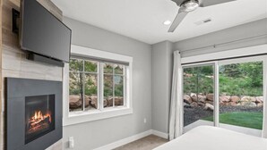 A modern room with a fireplace, a flat-screen TV, and large windows offering a view of the outdoors. - Perfect location! Come and see (Park City)