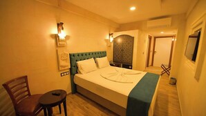 Una habitación de hotel con cama, una silla, una mesita y un adorno en la pared.