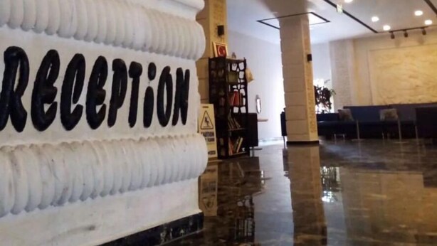 Un vestíbulo amplio con mostrador de recepción y un cartel grande que dice 'RECEPTION'.