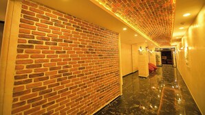 Un pasillo con pared de ladrillo, suelo de mármol e iluminación empotrada.