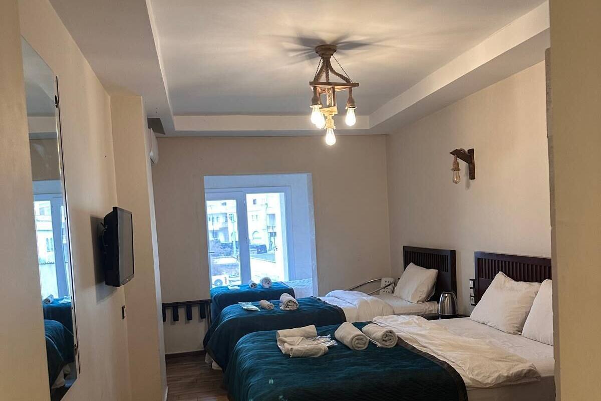 Ett hotellrum med två sängar, en takfläkt, en TV och ett fönster med utsikt.