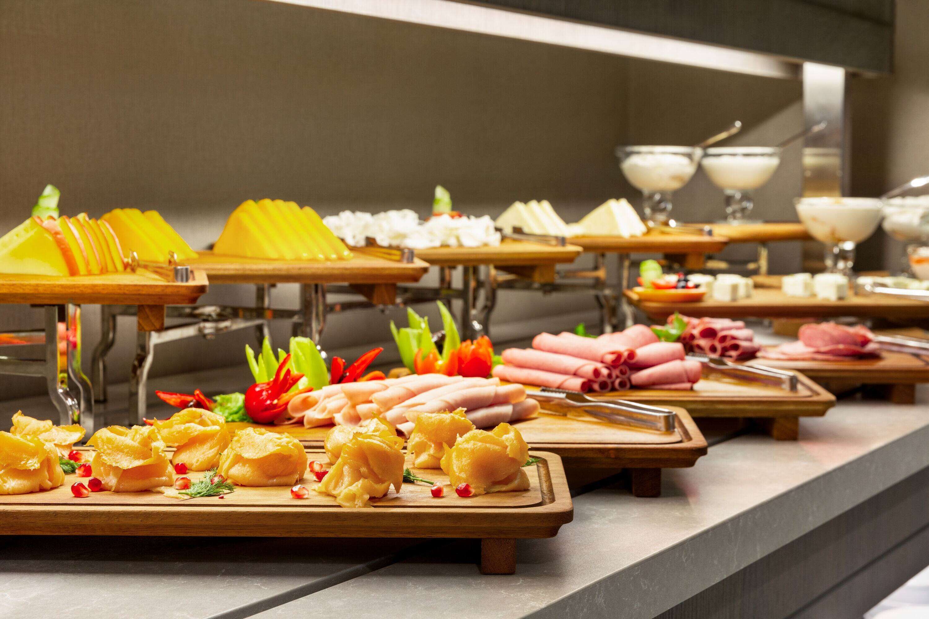 A buffet with various food items including fruits, cheeses, and meats.