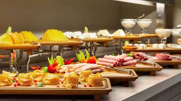 A buffet with various food items including fruits, cheeses, and meats.