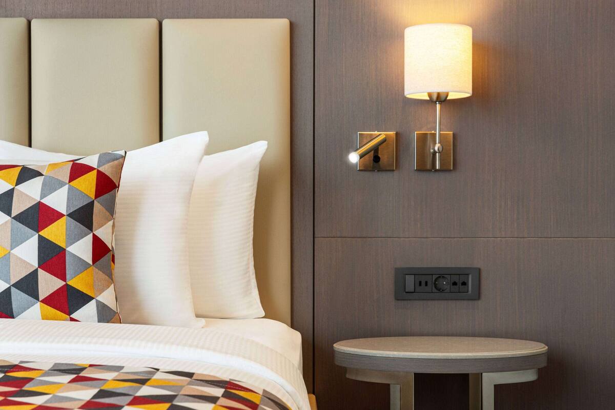 Une chambre d’hôtel équipée d’un lit, d’une table de chevet, d’une lampe et d’une prise électrique.