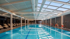 An indoor swimming pool with clear lane markings, a ceiling with skylights, and rows of sun loungers on one side. - Ramada Plaza By Wyndham Batumi (Batumi)