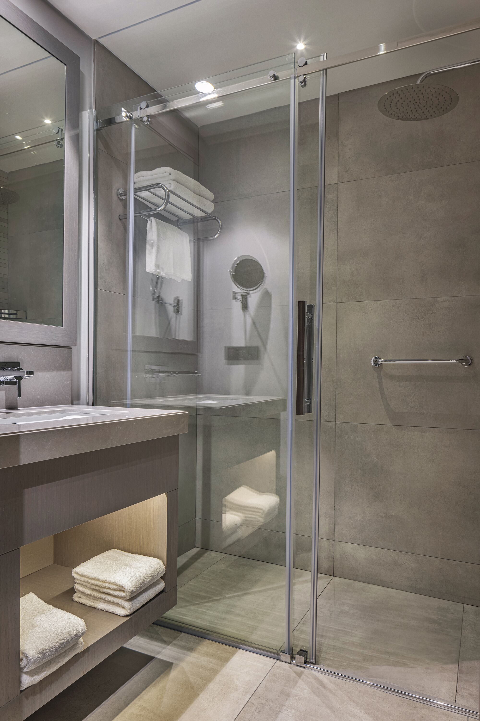 Un bany modern amb dutxa de vidre, un lavabo amb mirall i tovalloles ben plegades.
