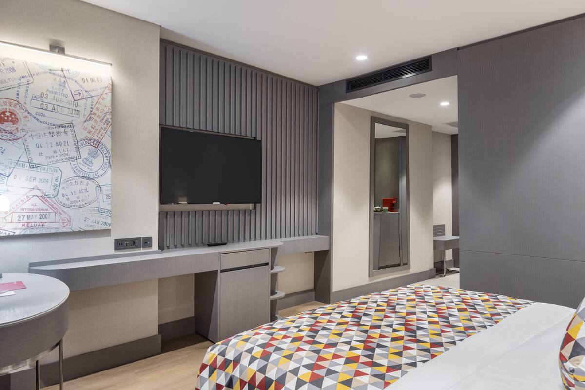 Une chambre d’hôtel moderne équipée d’un lit, d’un bureau, d’un téléviseur à écran plat et d’une carte affichée au mur.