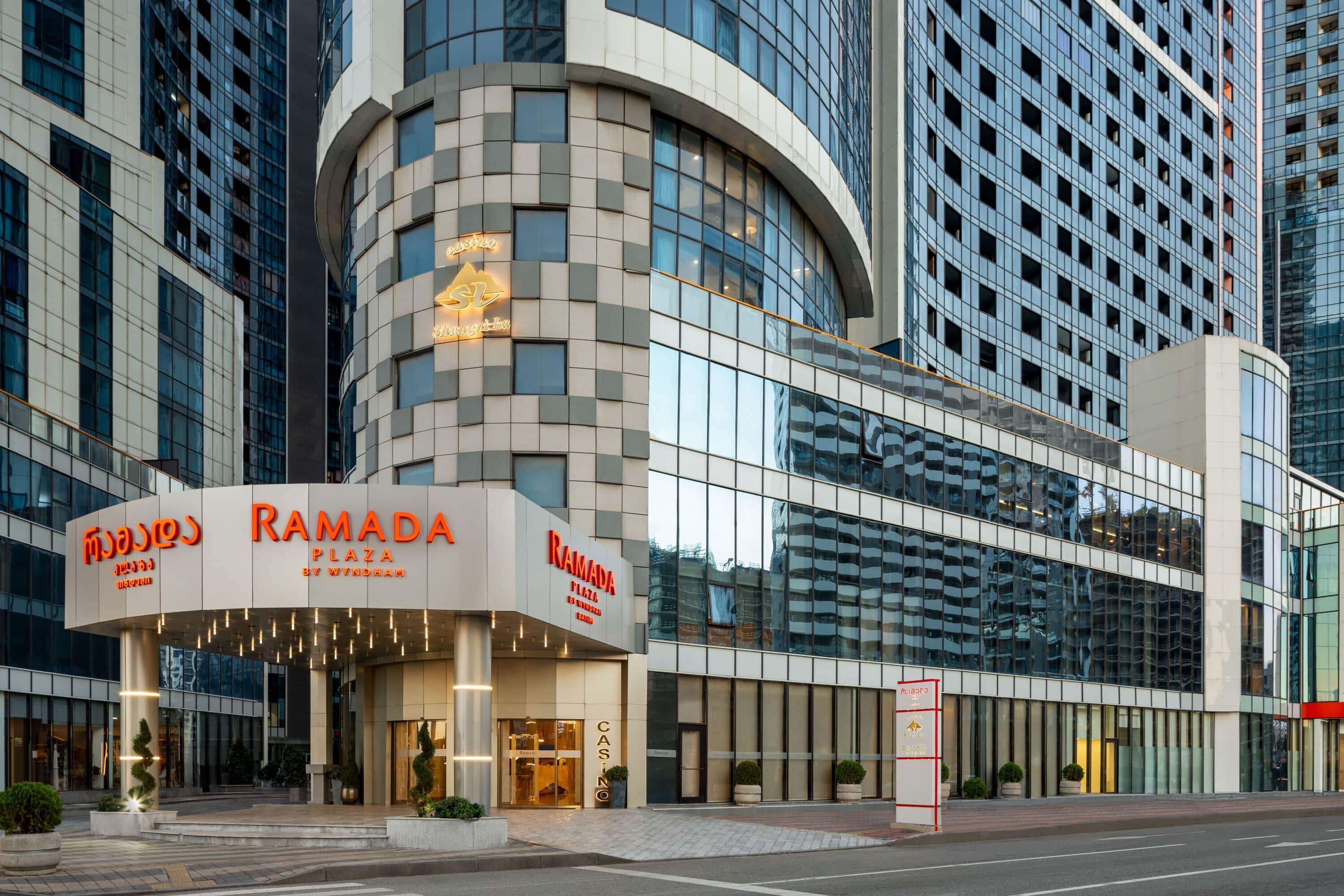 A modern building with a curved facade and a sign for "RAMADA PLAZA BY WINDSOR".