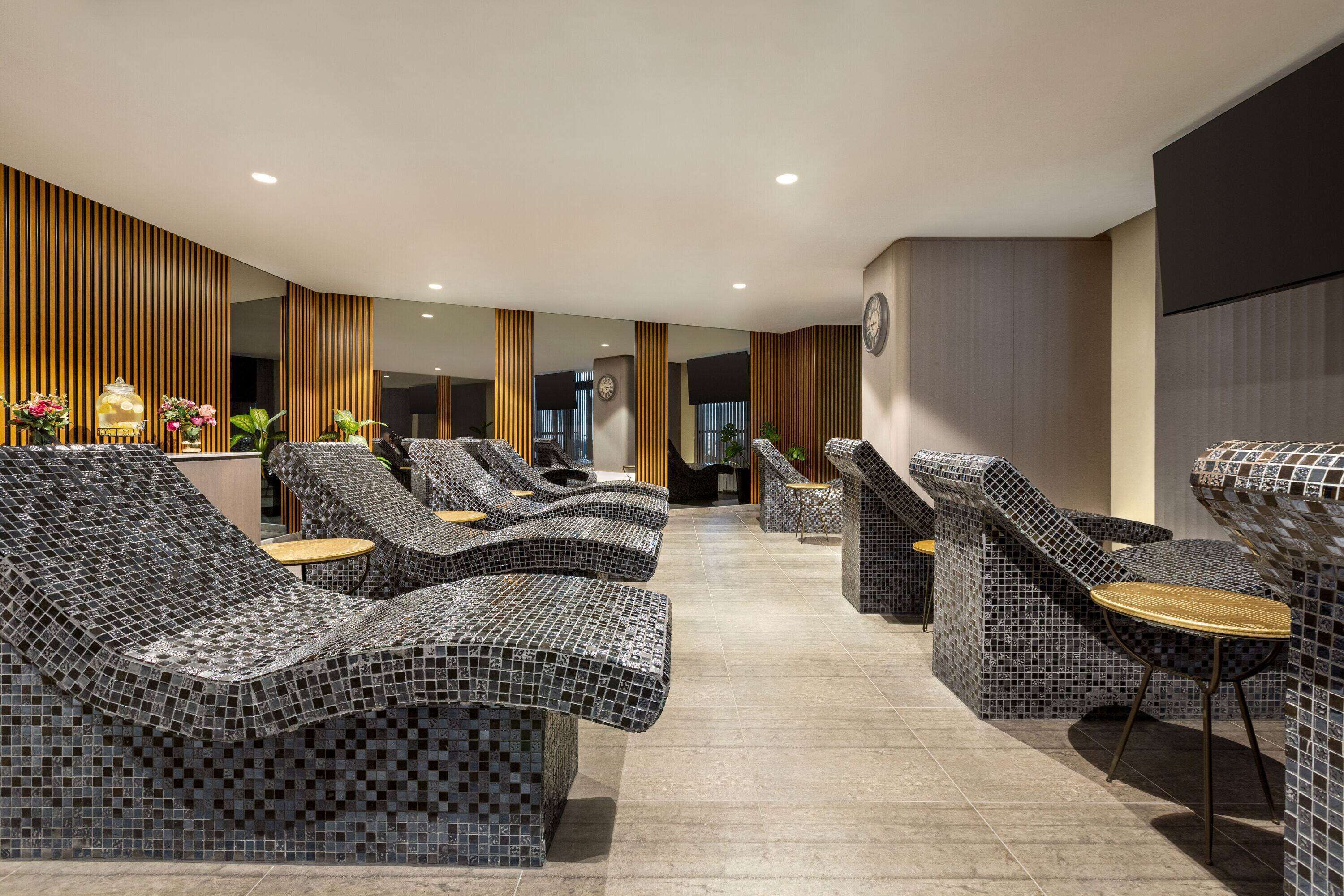 A modern lounge area with mosaic-patterned seating and a clock on the wall.