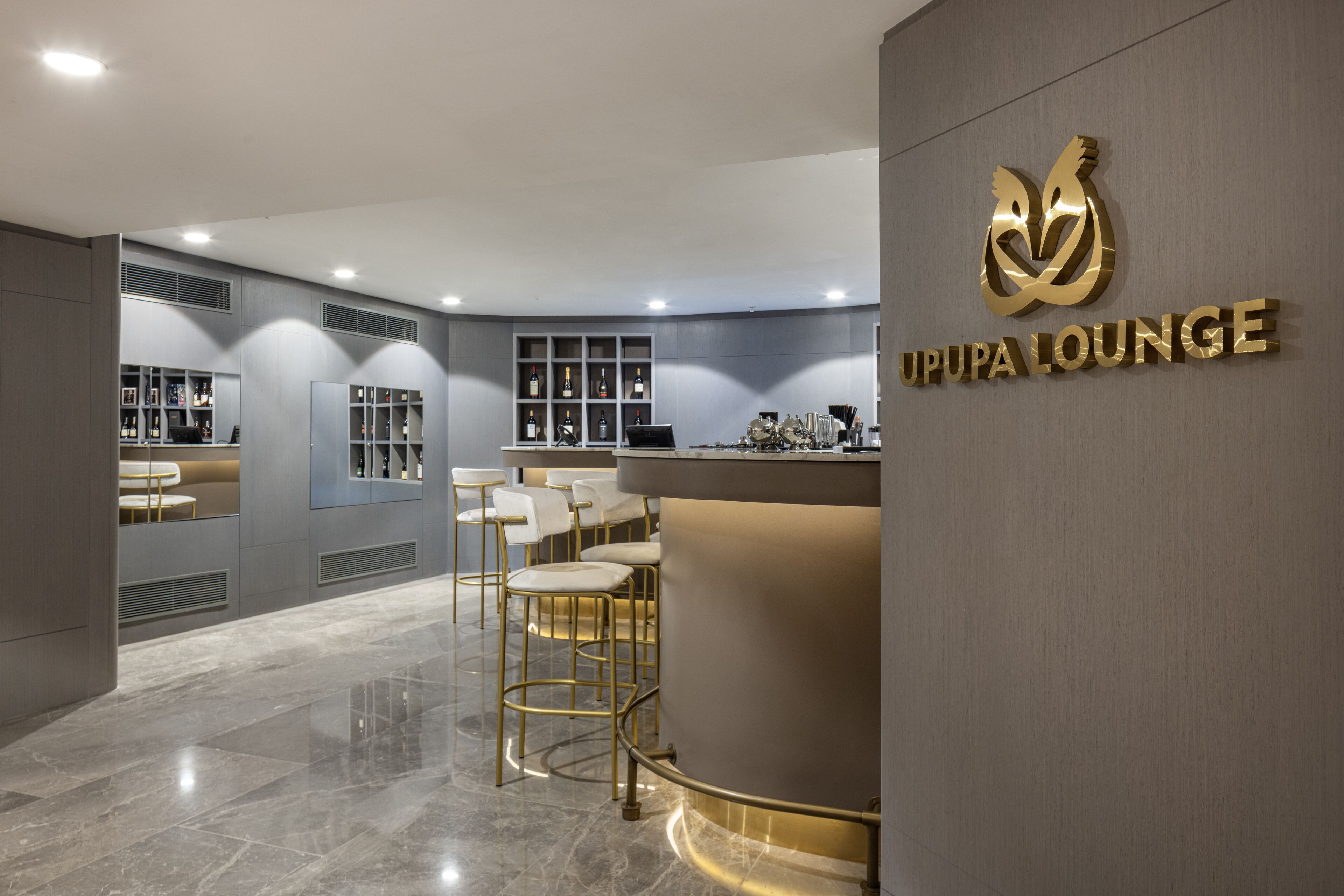 Un espace lounge moderne doté d’un bar, de sièges et d’une présentation de bouteilles.