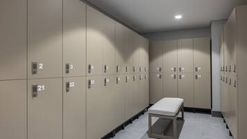 A row of beige lockers numbered 1 to 33, a bench, and a tiled floor.