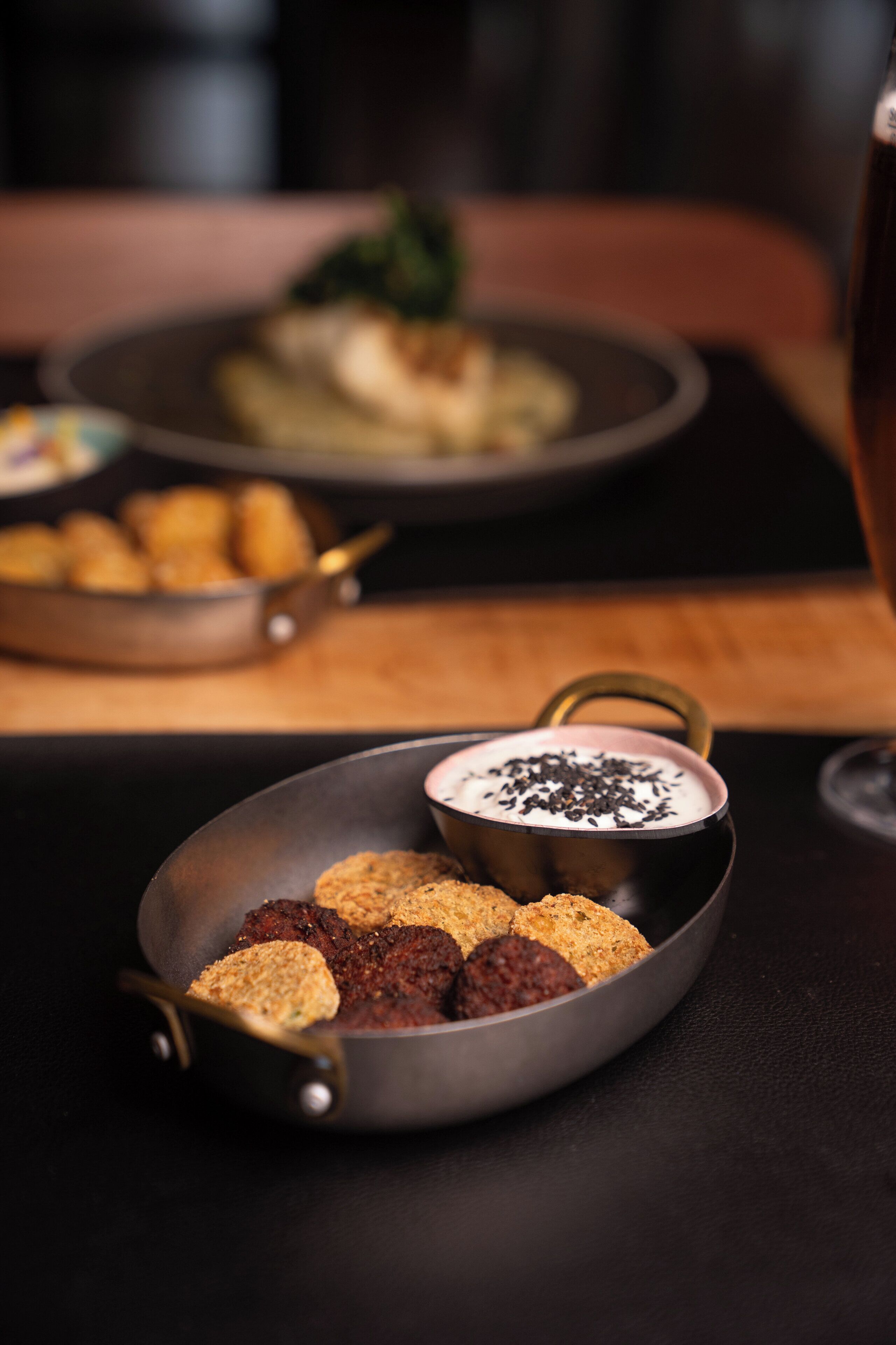 A dining table with a plate of food, a bowl of soup, and a glass of beverage.