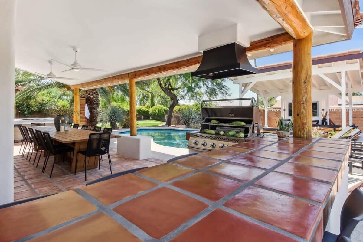 Eine Terrasse im Freien mit Grill, Pool und Essbereich.