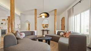 Een moderne woonkamer met een ronde salontafel, twee banken en een bijzondere hanglamp.