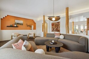 A modern living room with a sofa set, a coffee table, and a hanging light fixture. - Serene Home | Heated Pool & Games (Phoenix)