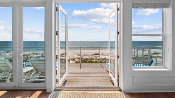 A room with a view of the beach through open doors.
