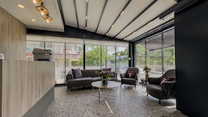 Een modern interieur met een bank, fauteuils en een salontafel. Grote ramen bieden uitzicht op het omliggende landschap.