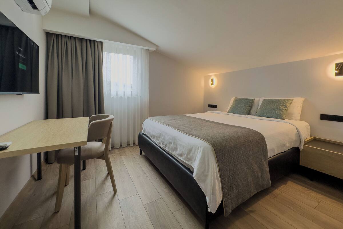 Een hotelkamer met een bed, bureau, stoel en televisie.