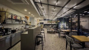 Een modern café met een bar, zitplaatsen en uitzicht door grote ramen.