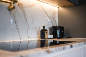 A kitchen with a marble countertop, a coffee maker, and a bottle of water.