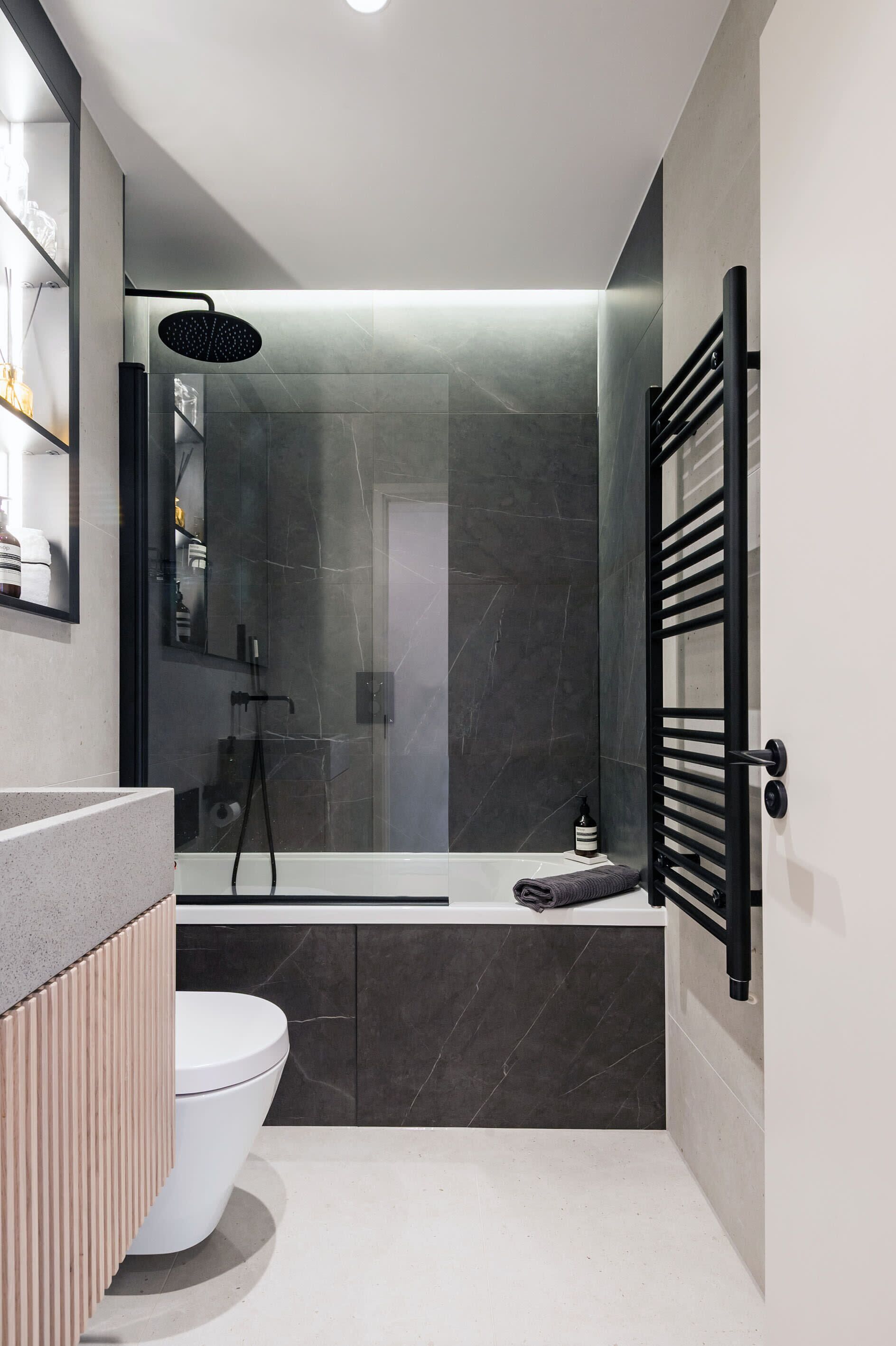 A modern bathroom with a toilet, a shower, and a towel rack.