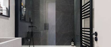 A modern bathroom with a toilet, a shower, and a towel rack.