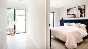 Ein modernes Schlafzimmer mit einem großen Bett, einer Deckenleuchte und Blick ins Freie.