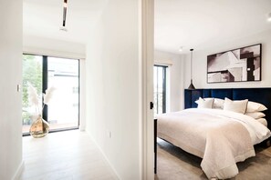 Ein modernes Schlafzimmer mit einem großen Bett, einer Deckenleuchte und Blick ins Freie.