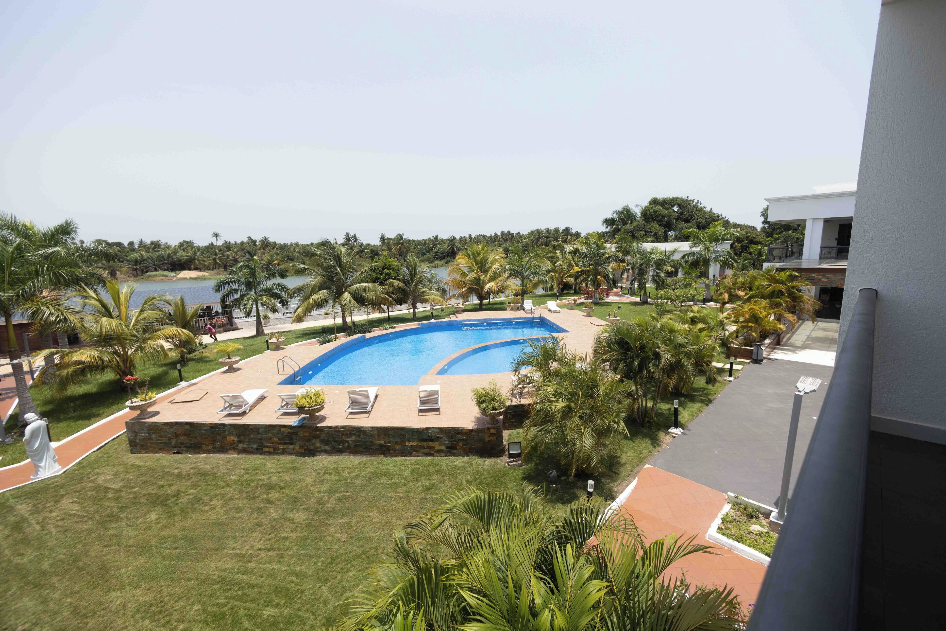 A swimming pool surrounded by palm trees and a view of the sea.