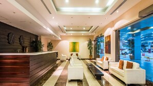 A modern lobby with a reception desk, seating area, and large windows overlooking a parking garage.