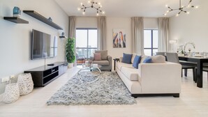 A modern living room with a flat-screen TV, sofa, coffee table, and decorative items.