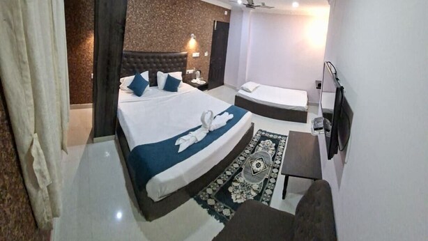 A modern hotel room with a large bed, a desk, a chair, and a ceiling fan. - Hotel Pigeons Nest (Port Blair)
