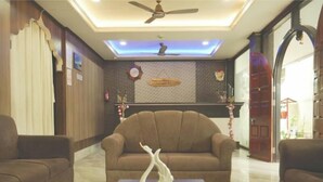A living room with a brown sofa, a wooden coffee table, and a decorative swan. - Hotel Pigeons Nest (Port Blair)