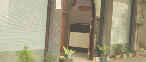 A hotel entrance with a sign reading "Hotel Pigeon". There are potted plants outside the entrance.