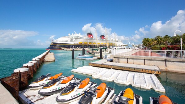 A cruise ship docked at a pier with several jet skis lined up at the dock.