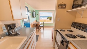 Una cocina compacta con estufa, lavamanos y zona de comedor.